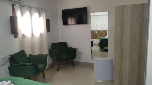 a living room with two green chairs and a mirror at Pousada Villa Goyá in São José da Coroa Grande