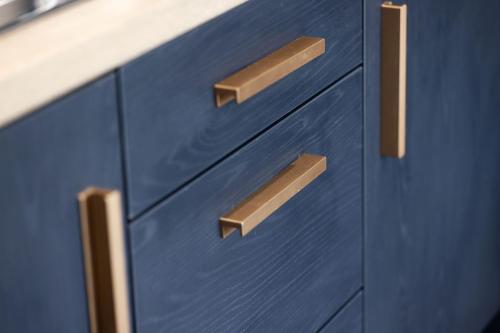 a blue kitchen cabinet with wooden handles at Pierside Apartments Deluxe Accommodation in Portsalon