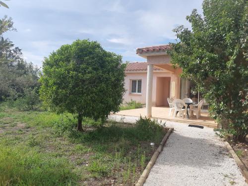 une maison avec une terrasse, une table et un arbre dans l'établissement Villa de standing avec gd jardin arboré près d'Argelès sur Mer, à Saint-André