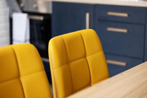 two yellow chairs sitting next to a desk at Pierside Apartments Deluxe Accommodation in Portsalon