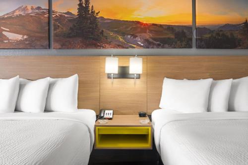 two beds in a hotel room with paintings on the wall at Days Inn by Wyndham Columbus Worthington in Columbus