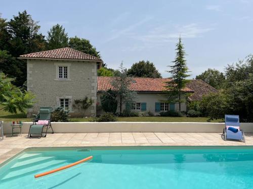 une piscine avec deux chaises et une maison dans l'établissement Vaste propriété de charme au cœur du Périgord vert, à Siorac-de-Ribérac