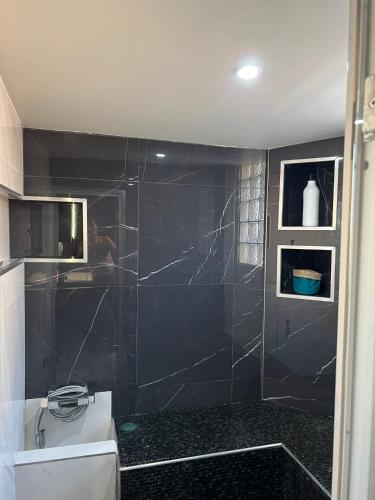 une salle de bain avec une douche carrelée noire et un lavabo dans l'établissement villa Wamal, à Mauguio