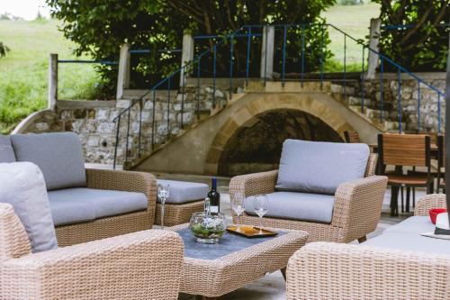 une terrasse avec des chaises en osier et une table avec des verres à vin dans l'établissement Domaine de Pérenard, à Bergerac