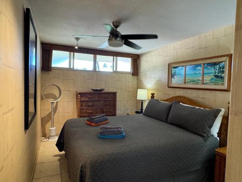 a bedroom with a bed with a ceiling fan at Tropical Hawaiian Oceanfront - indigomaui - KR210 in Kahana