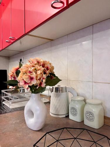 a white vase with flowers in it next to two candles at Apartment Sofija in Kotor