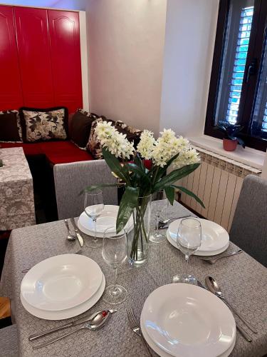 a table with plates and a vase of flowers on it at Apartment Sofija in Kotor