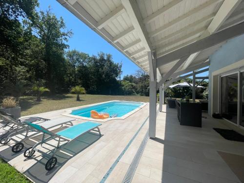 - une piscine avec 2 chaises longues sur la terrasse dans l'établissement Villa avec piscine à Casteljaloux, à Casteljaloux