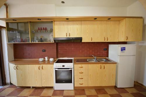 a kitchen with wooden cabinets and a sink and a refrigerator at Fishta Villa and Apartments in Shkodër