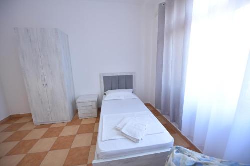 a small room with a white bed and curtains at Fishta Villa and Apartments in Shkodër