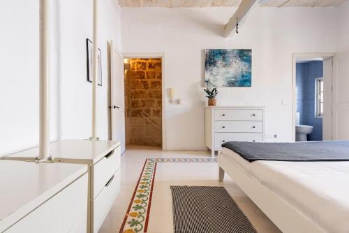 a white bedroom with a bed and a dresser at Our Nest in Il-Furjana