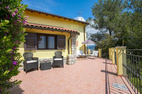 a patio of a house with chairs and an umbrella at Villa Monte Enrico - Pool And Whirlpool - Happy Rentals in Camporosso