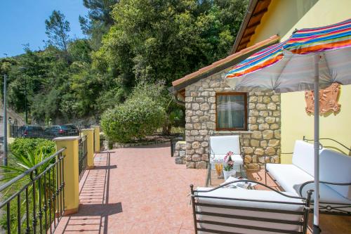 a patio with chairs and an umbrella and a building at Villa Monte Enrico - Pool And Whirlpool - Happy Rentals in Camporosso