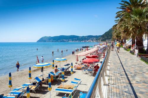 a beach with chairs and umbrellas and people in the water at Villa Monte Enrico - Pool And Whirlpool - Happy Rentals in Camporosso
