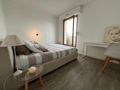 une chambre avec un lit, un bureau et une fenêtre dans l'établissement Eiffel tower view appartment, à Suresnes