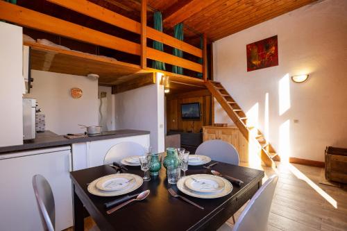 une salle à manger avec une table noire et une cuisine dans l'établissement Résidence Grand Roc - Studio 708 - Happy Rentals, à Chamonix-Mont-Blanc