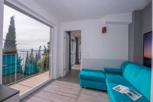 salon z niebieską kanapą i dużym oknem w obiekcie Rustichel Fantastic Lake View - Happy Rentals w mieście Toscolano Maderno