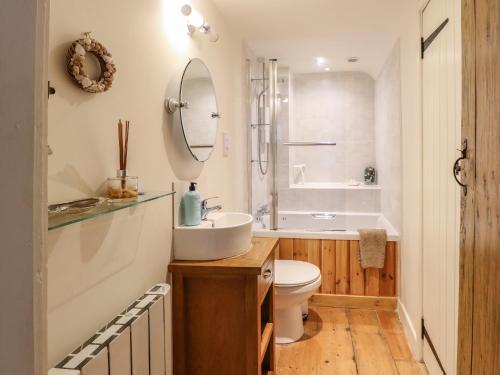 a bathroom with a sink and a toilet and a tub at Beach Cottage in Holt