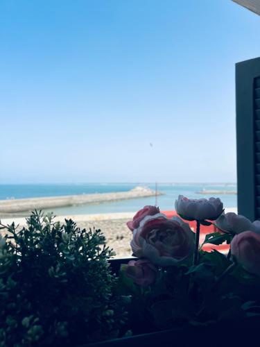 a bunch of roses sitting on a table near the beach at Art riad au bord de la mer 2 in El Jadida