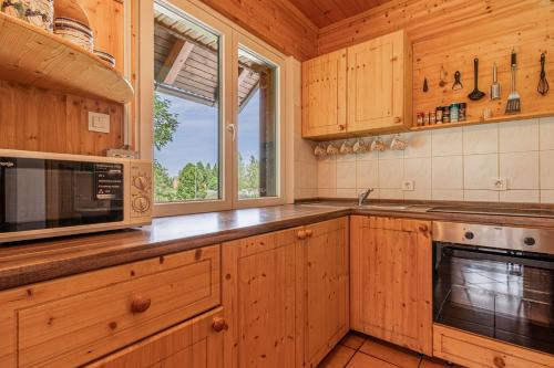 cocina con armarios de madera, microondas y ventana en Family Friendly Kraševec Lodge - Happy Rentals, en Velike Bloke