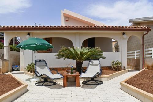 patio z 2 krzesłami, stołem i parasolem w obiekcie Casa Apara- Happy Rentals w mieście Scicli