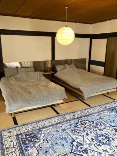two beds in a room with a rug at 小グループ専門貸切一軒家 パーティーOK観光スポット徒歩圏内 小諸駅歩2分揚羽屋 Specializing in small groups, Party OK, Walking to tourist spots, Vacation Rental House 2 min from Komoro sta in Komoro