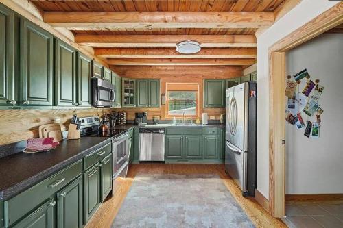 a kitchen with green cabinets and a refrigerator at Awesome Log Cabin in Massanutten Resort in McGaheysville