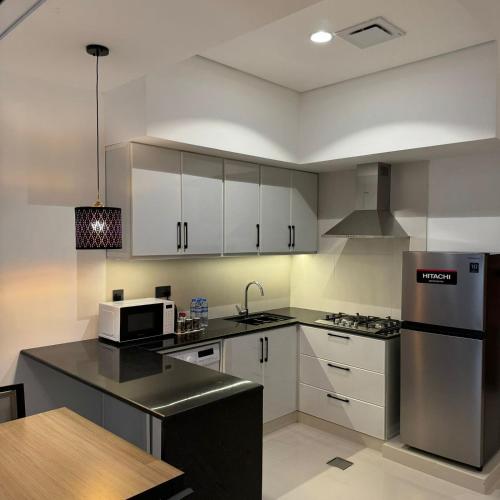 a kitchen with white cabinets and a stainless steel refrigerator at واجهة السعادة للشقق الفندقية in Salalah