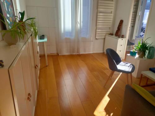 a living room with a chair and wooden floors at Appartement moderne à Clichy, 35 m², idéal pour 4 personnes. in Clichy