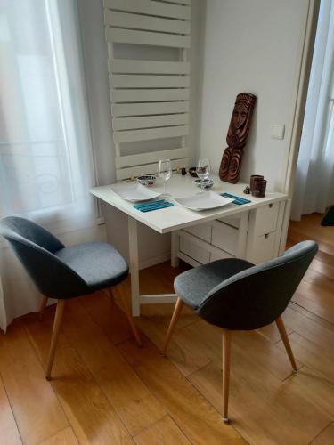 - un bureau blanc avec 2 chaises et des verres à vin dans l'établissement Appartement moderne à Clichy, 35 m², idéal pour 4 personnes., à Clichy