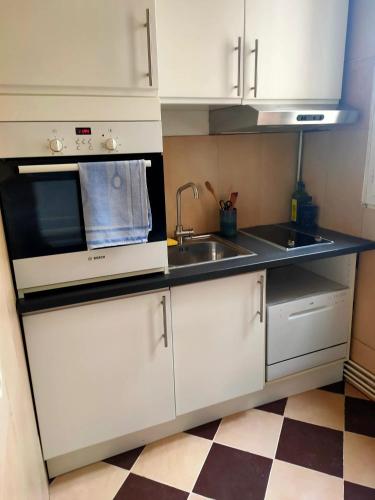 une cuisine blanche avec un évier et un micro-ondes dans l'établissement Appartement moderne à Clichy, 35 m², idéal pour 4 personnes., à Clichy