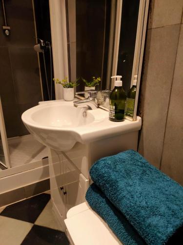 La salle de bains est pourvue d'un lavabo blanc et d'une serviette bleue. dans l'établissement Appartement moderne à Clichy, 35 m², idéal pour 4 personnes., à Clichy