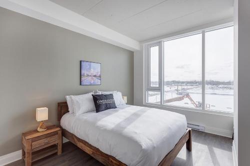a bedroom with a large bed and a large window at L'Equinox Modern Apartments by Corporate Stays in Laval
