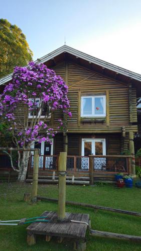 a house with a tree with purple flowers in front of it at Aldeia Flor de Liz - Pedra Azul in Pedra Azul