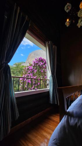 a bedroom with a window with a view of flowers at Aldeia Flor de Liz - Pedra Azul in Pedra Azul