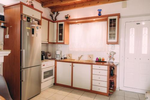 a kitchen with white cabinets and a refrigerator at Yiannis' Maizonette Ancient Olympia - Happy Rentals in Olympia