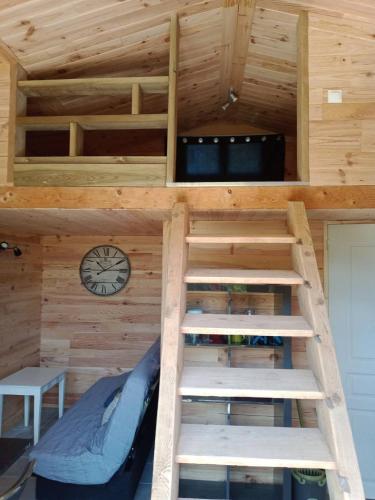 un lit mezzanine dans une petite maison avec une horloge dans l'établissement Chalet au calme, à Coullons