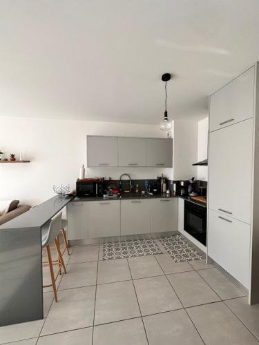 une cuisine avec des armoires blanches et un sol carrelé dans l'établissement Charmant 2 pièce tout équipé climatisé, à Sainte-Lucie de Porto-Vecchio