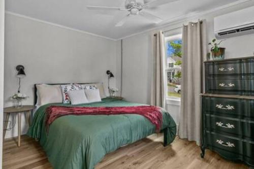 a bedroom with a bed with a green blanket and a window at Updated, Fenced, Pet Friendly Downtown Cottage in Southern Pines