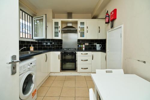 a kitchen with white cabinets and a washer at MODERN LONDON DOUBLE Bedroom in London