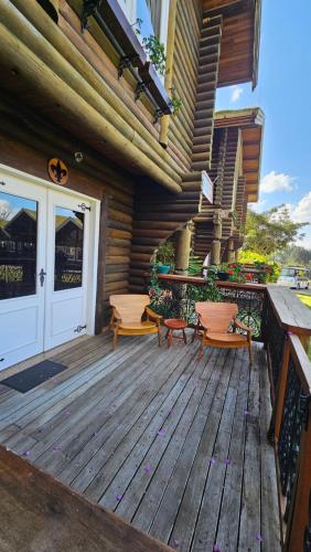 a wooden deck with two chairs and a door at Aldeia Flor de Liz - Pedra Azul in Pedra Azul