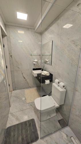 a bathroom with a toilet and a glass shower at Aldeia Flor de Liz - Pedra Azul in Pedra Azul