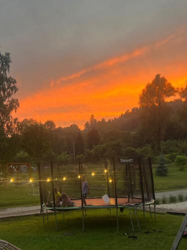 a couple of people sitting on a bed at sunset at Solny - Resort w Bieszczadach in Cisna