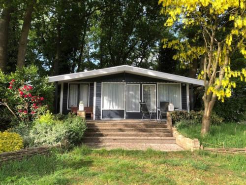 a small house with a porch and stairs to it at Gezellig vrijstaand huisje in een mooie omgeving in Schipbork