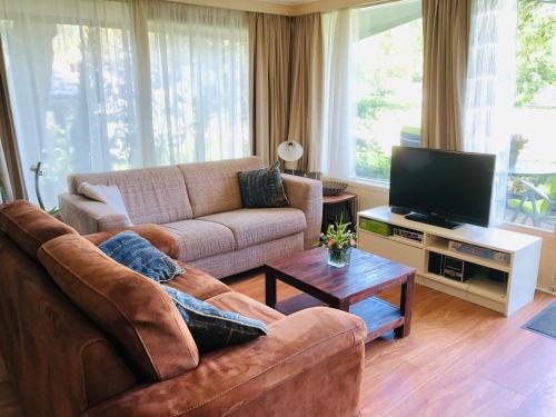 a living room with a couch and a flat screen tv at Gezellig vrijstaand huisje in een mooie omgeving in Schipbork