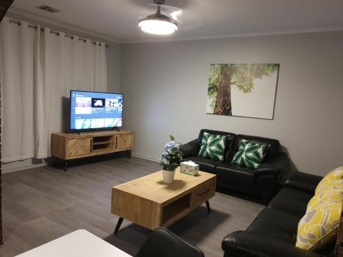 a living room with a couch and a tv at Cottage BNB near the hill in Teatree Gully