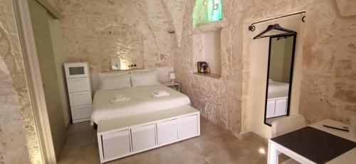 a small bedroom with a white bed and a mirror at La Vernèa in Ceglie Messapica