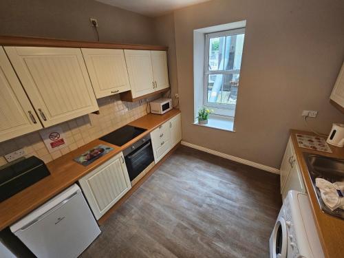 a small kitchen with white cabinets and a window at Latin Quarter Townhouse in Galway