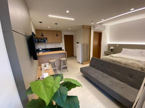a room with a bed and a couch and a kitchen at Monte Carmel in Ribeirão Preto