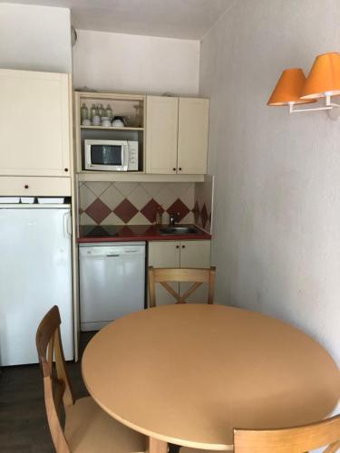 une petite cuisine avec une table et un micro-ondes dans l'établissement Appartement 1 chambre - Chamonix, à Chamonix-Mont-Blanc